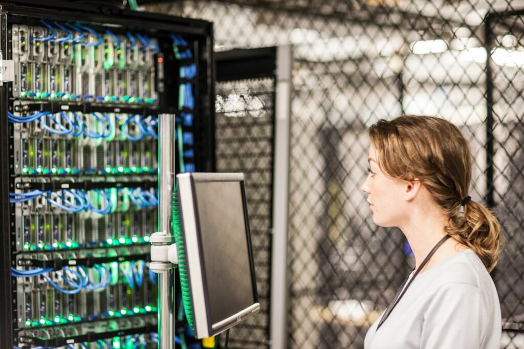 Caucasian woman technician doing diagnostic tests on computer servers in a server farm.