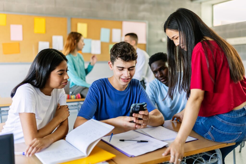 Multiracial group of student friends watching social media content on smartphone